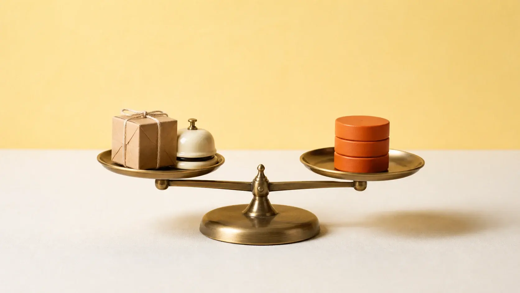 A balance scale weighing a parcel and service bell against unmarked value tokens